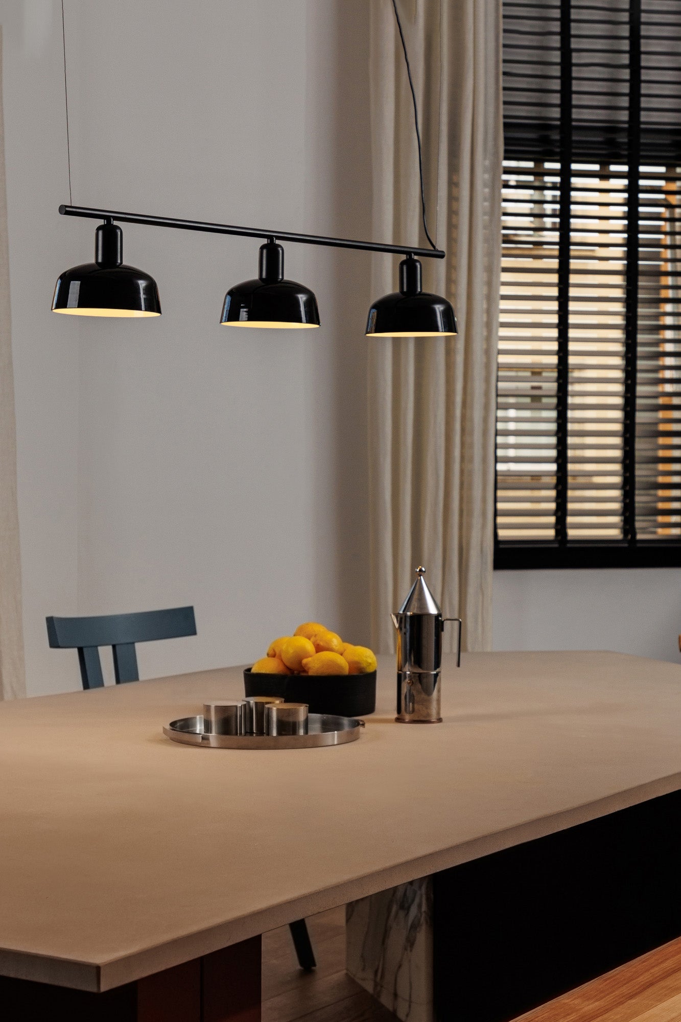 Faro Barcelona Tatawin medium 3 light linear pendant in Black, hanging over a dining table